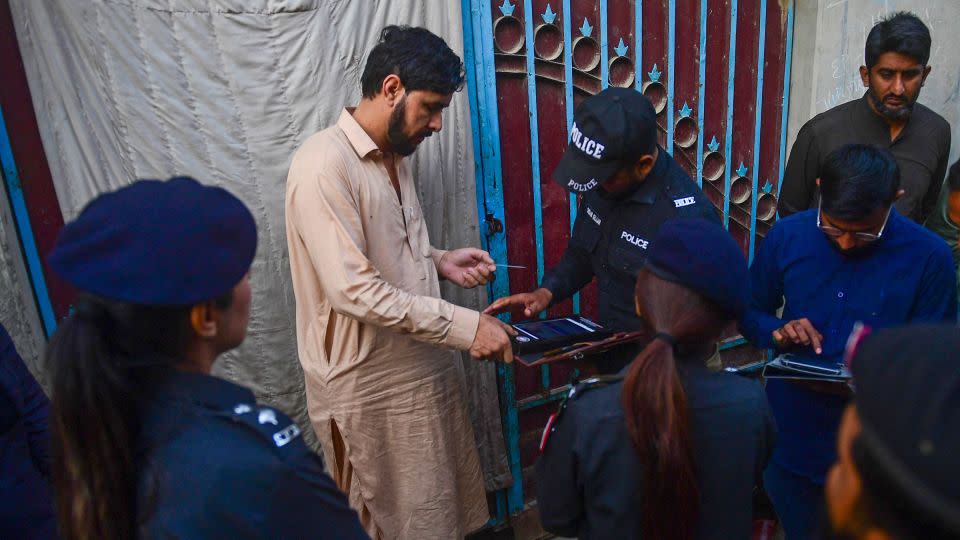 Police test the biometrics of an Afghan refugee during a search operation to identify undocumented immigrants, on the outskirts of Karachi on November 17, 2023. - Asif Hassan/AFP/Getty Images