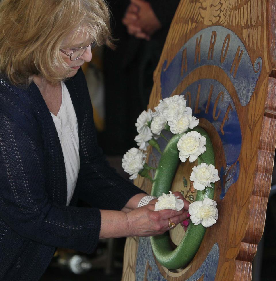 Fran Sandor, a member of the Akron FOP Auxiliary 1 places a flower on the wreath to honor an Akron Police officer who has died while serving the department during the Akron Police Memorial Day ceremony at the Fraternal Order of Police Akron Lodge 7 on Wednesday. 