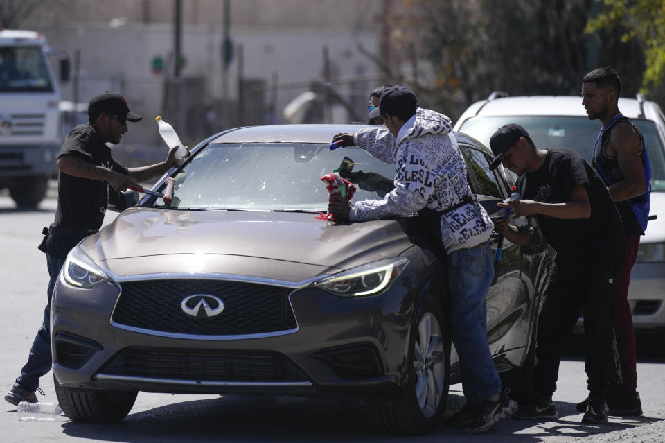 Migrants from Venezuela and Guatemala wash windshields for tips at a stoplight in Ciudad Juarez, Mexico, Thursday, March 30, 2023. (AP Photo/Fernando Llano)