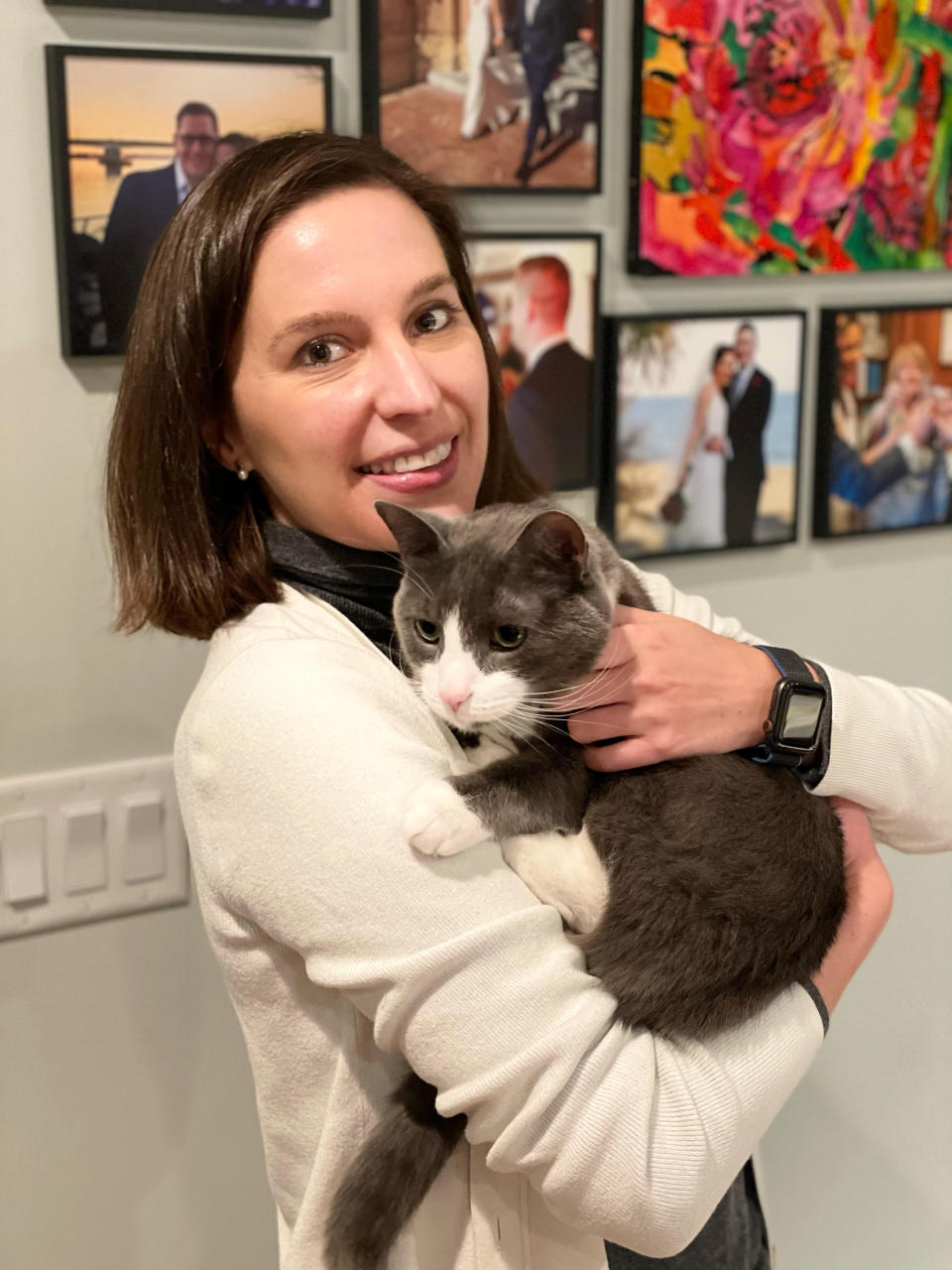 In this photo provided by Mike Thom, Mike Thom's wife, Emily Benavides, poses with her cat, Humito, Dec. 9, 2020, in Washington. Benavides, a U.S. Senate staffer, is learning her cat's language. Humito (Spanish for Smokey), the 3-year-old rescue cat she's had most of his life, has different-sounding “Meows” to communicate that he wants to eat, wants to nap or has knocked his toy under the refrigerator. (Mike Thom via AP)