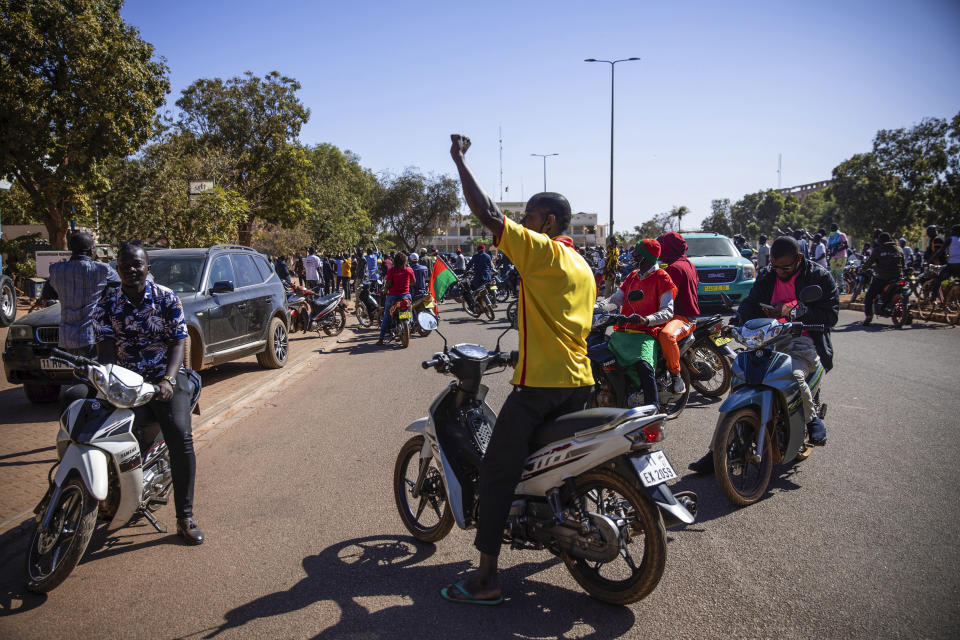 People cheer in support of putschist soldiers near the national television station in Ouagadougou, Monday Jan. 24, 2022. Two mutinous soldiers told The Associated Press that Burkina Faso’s President Roch Marc Christian Kabore is being held by the rebellious soldiers. Gunshots rang late Sunday night near the president’s residence and in the early hours of Monday a battle took place at the presidential palace while a helicopter flew overhead. (AP Photo/Sophie Garcia)