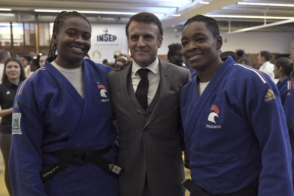 French President Emmanuel Macron, centre, poses for a photo with Frency judokas Romane Diko, left and Audrey Tcheumeo, as he visits France's National Institute of Sport, Expertise, and Performance (INSEP), prior to presenting his New Year's wishes to elite athletes ahead of the Paris 2024 Olympic and Paralympic Games, in Paris, Tuesday, Jan. 23, 2024. (Stephane De Sakutin/Pool Photo via AP)