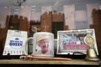 Windsor Castle is reflected in the window of a shop selling Royal souvenirs outside the Castle, in Windsor, England, Friday, Oct. 22, 2021. Britain's Queen Elizabeth II spent a night in a hospital for checks this week after canceling an official trip to Northern Ireland on medical advice, Buckingham Palace said Thursday. The palace said the 95-year-old British monarch went to the private King Edward VII's Hospital in London on Wednesday for "preliminary investigations." It said she returned to her Windsor Castle home at lunchtime on Thursday, "and remains in good spirits. (AP Photo/Kirsty Wigglesworth)
