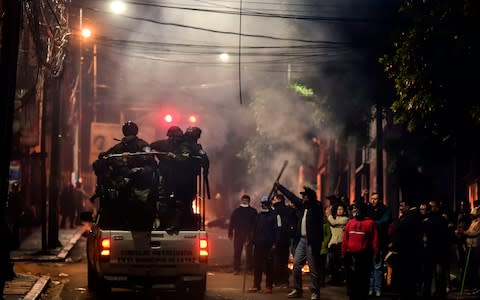 People gesture at policemen as they patrol the streets in La Paz - Credit: RONALDO SCHEMIDT/AFP