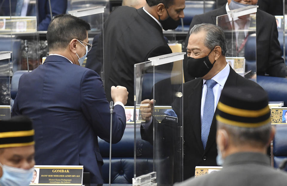 In this photo release by Malaysia Information Ministry, Malaysia's Prime Minister Muhyiddin Yassin, right, fist-bumps with Minister of International Trade and Industry Azmin Ali after the budget 2021 vote during a session of the lower house of parliament, in Kuala Lumpur, Malaysia Thursday, Nov. 26, 2020. Malaysia's Parliament Thursday approved the government's proposed 2021 budget, throwing a political lifeline to embattled Prime Minister Muhyiddin Yassin amid strong resistance to his nine-month-old leadership. (Famer Roheni/Malaysia's Department of Information via AP)
