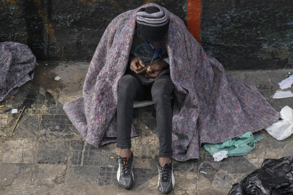 A homeless drug user smokes crack cocaine in the Santa Efigenia shopping district, a major commercial hub for electronics, technology products, and accessories in downtown Sao Paulo, Brazil, Thursday, May 18, 2023. Once limited to a few blocks around the Julio Prestes train station, the city's so-called "Crackland" has extended into surrounding neighborhoods, including the city's most popular district for electronics. (AP Photo/Andre Penner)