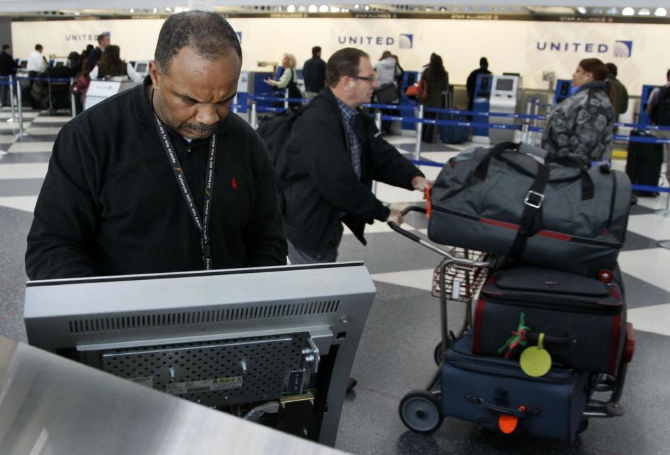 David Caradine works at upgrading the software at a United Airlines e-ticket kiosk at Chicago's O'Hare International Airport Thursday, Nov. 15, 2012. Passengers in several cities say a massive computer outage has stranded United passengers at airports across the country, resulting in at least the third major computer outage for the Chicago-based airline since June. (AP Photo/Charles Rex Arbogast)