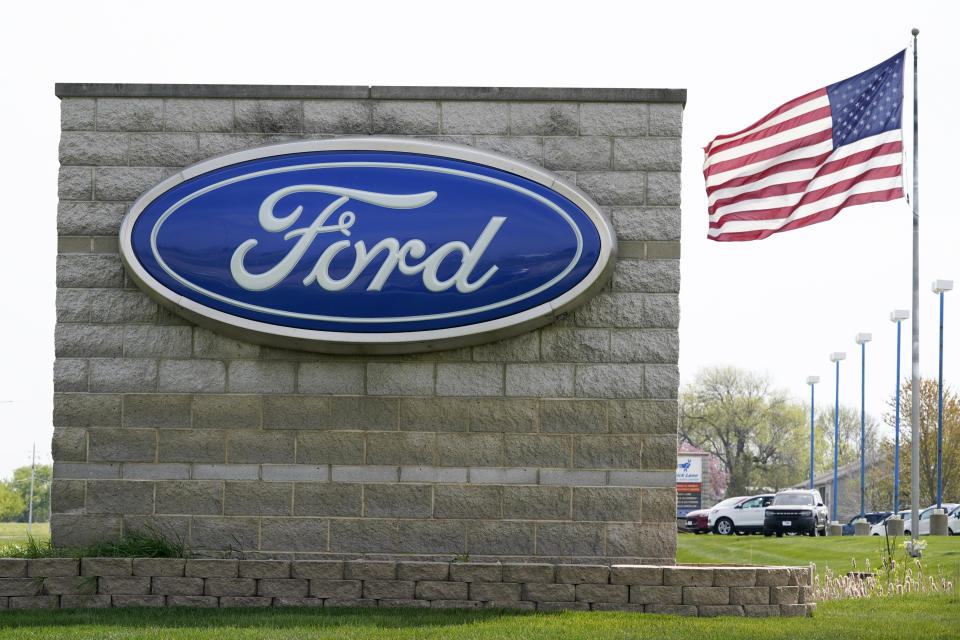 FILE - In this April 27, 2021 file photo, an American flag flies over a Ford auto dealership, in Waukee, Iowa. Ford says it expects 40% of its global sales to be battery-electric vehicles by 2030 as it adds billions to the amount its spending to develop them. Ahead of a presentation to Wall Street on Wednesday morning, May 26 the automaker says it will add about $8 billion to its EV development spending from this year to 2025. (AP Photo/Charlie Neibergall, File)