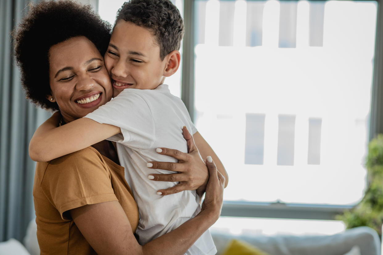 Cute boy hugging with his mother at home