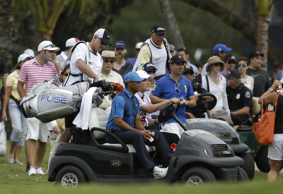 Tiger Woods, center, gets a ride in a cart with his caddy Joe LaCava, left, after play was suspended due to approaching inclement weather during the first round of the Cadillac Championship golf tournament, Thursday, March 6, 2014, in Doral, Fla. (AP Photo/Lynne Sladky)