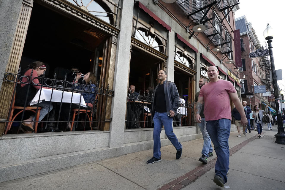 FILE - In this March 25, 2021, file photo, people, right, walk past diners seated near open windows, left, in a restaurant on a busy street in the historic North End neighborhood of Boston. In Massachusetts, where the seven-day rolling average of daily new cases has risen to over 2,100 new cases per day, the Massachusetts Public Health Association called on Republican Gov. Charlie Baker to reinstate public health measures. The group urged Baker to limit indoor dining capacity and other indoor activities, saying the rise in cases and hospitalizations followed Baker's decision to loosen those restrictions. (AP Photo/Steven Senne, File)