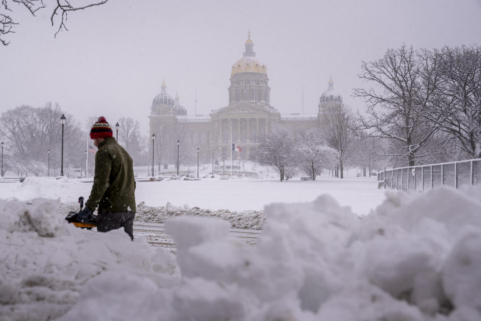 The Iowa State Capitol Building is visible as Spud Glaser of Carlisle, Iowa, plows the sidewalk in downtown Des Moines, Iowa, Tuesday, Jan. 9, 2024, as a winter snow storm hits the state. (AP Photo/Andrew Harnik)