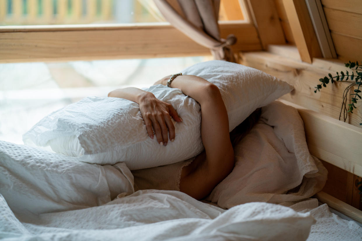 Woman with pillow on face, tired and frustrated with stress, nightmare or dream