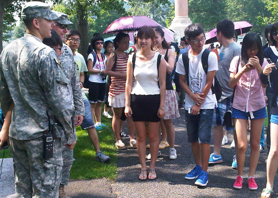 In this photo of Aug. 3, 2012, a tourist poses with cadets for a photo as others wait their turn during a tour of the U.S. Military Academy at West Point, N.Y. Suburbs in the New York metropolitan area are stepping up their efforts to attract tourist dollars, not by competing with New York City, but by marketing themselves as complementary destinations. (AP Photo/Jim Fitzgerald)