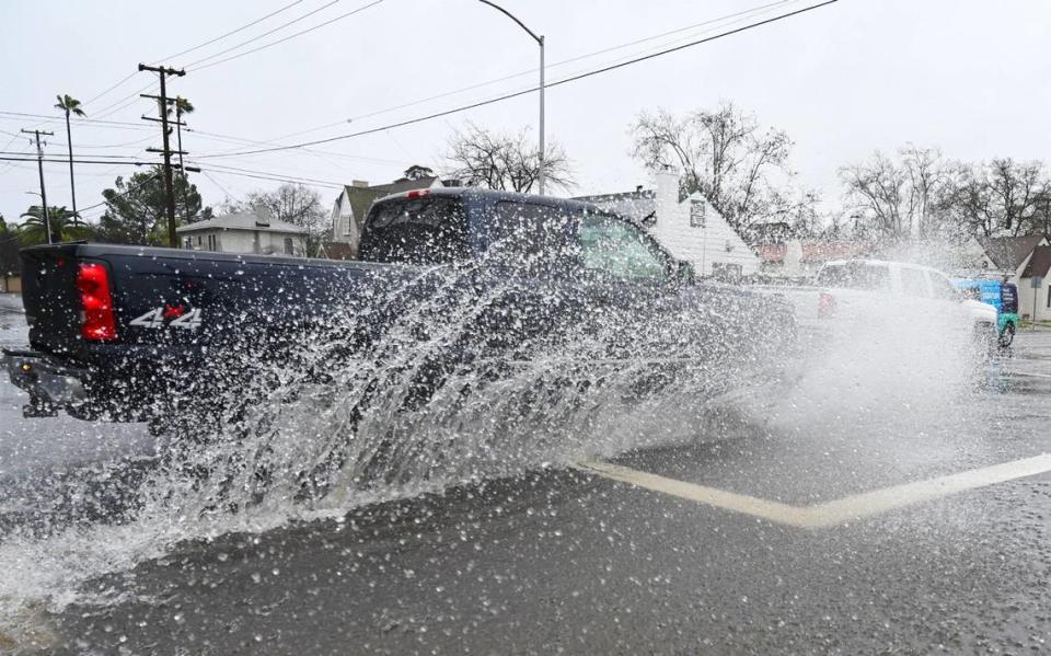 Westbound traffic along Clinton Ave. splashes through the flooded intersection at Maroa Avenue as an atmospheric river continues to dump rain Monday, Jan. 9, 2023 in Fresno. ERIC PAUL ZAMORA/ezamora@fresnobee.com