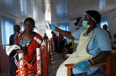 A health worker checks the temperature of a woman as part of the ebola screening, in Mpondwe