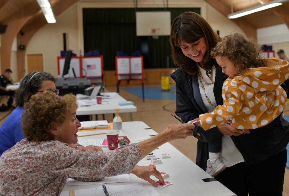 Senate candidate Robyn Kennedy holds niece Gianna, 2, as a poll worker hands her a sticker on Tuesday at the Salem Covenant Church polling place.