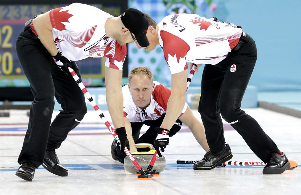 Canada's skip Brad Jacobs, center, delivers the rock to his sweepers, Ryan Harnden, left, and E.J. Harnden, right, during the men's curling competition against Germany at the 2014 Winter Olympics, Monday, Feb. 10, 2014, in Sochi, Russia. (AP Photo/Wong Maye-E)