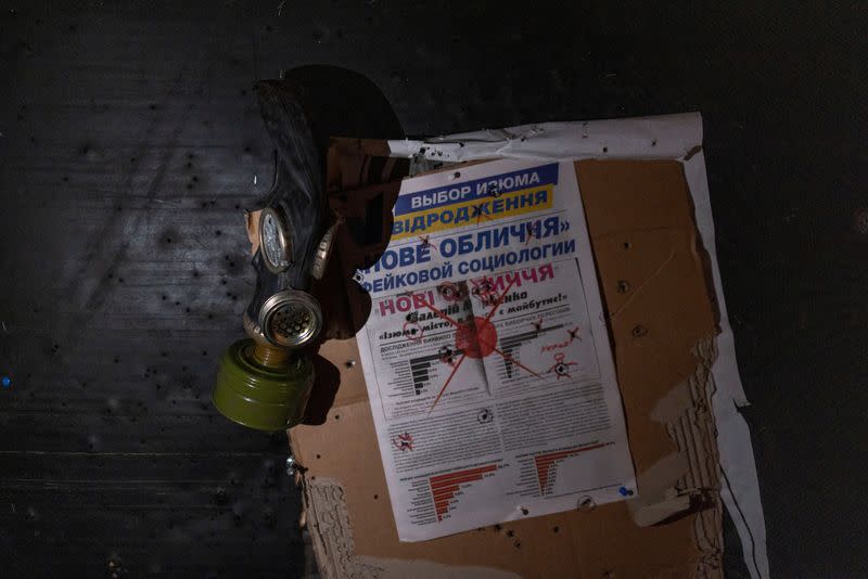 A view of a newspaper and a gas mask hung on a wall at a room in a police station which a Ukrainian serviceman says was used as a torture chamber by Russian soldiers in the town of Izium