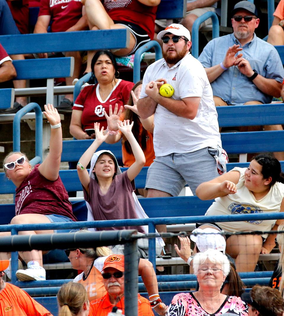 A fan catches a foul ball in the stands during the Big 12 softball championship game between OU and OSU on May 15 at the USA Softball Hall of Fame Complex.