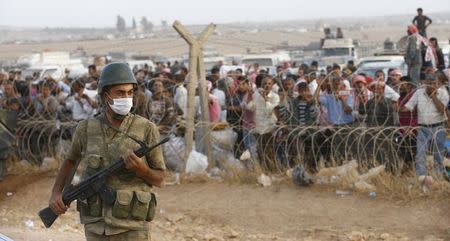 A Turkish soldier stands guard as Syrian Kurdish refugees wait behind the border fences to cross into Turkey near the southeastern town of Suruc in Sanliurfa province September 27, 2014. REUTERS/Murad Sezer