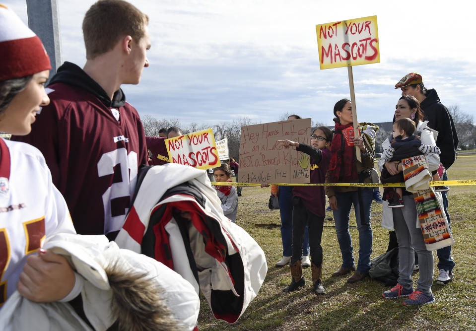 Fans of the Washington football team walk past as Native Americans and supporters protest the team's name and logo before the game on Dec. 28, 2014. (Tony L. Sandys / The Washington Post via Getty Images)