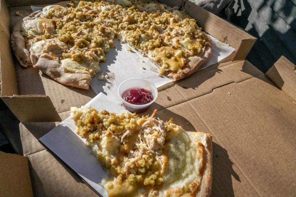 Fellini's Thanksgiving pizza is topped with mozzarella cheese, mashed potatoes, turkey, stuffing and gravy and served with a side of cranberry sauce.