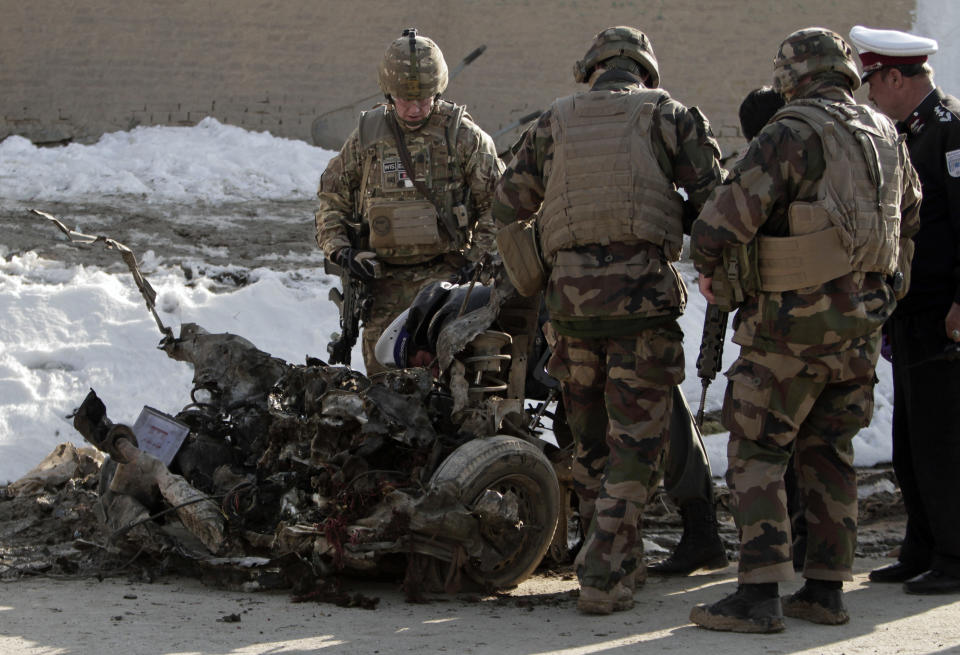 U.S. soldiers search the site where a suicide attacker rammed a car bomb into a NATO convoy killing two foreign civilian contractors, in the Afghan capital Kabul, Afghanistan, Monday, Feb. 10, 2014. The Islamic militant group Hizb-i-Islami claimed responsibility for the attack in eastern Kabul, saying it would drive all foreign forces from Afghanistan. (AP Photo/Rahmat Gul)