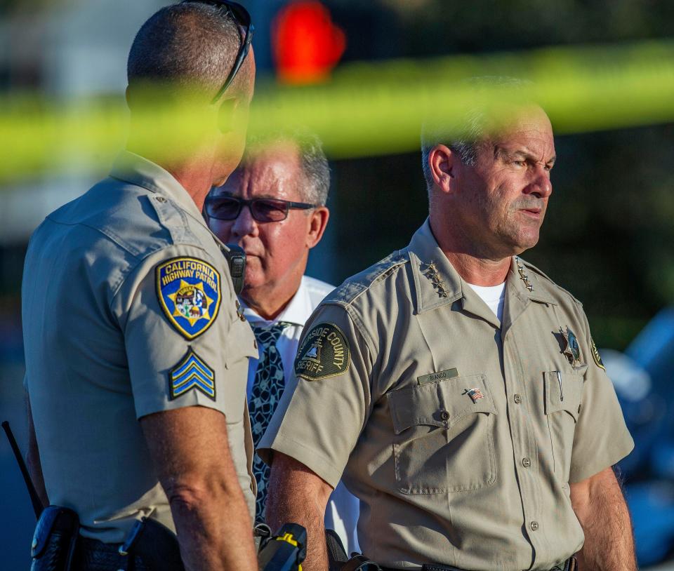 Riverside County Sheriff Chad Bianco, right, with Riverside City Police Chief Sergio G. Diaz, center, and a California Highway Patrol officer gather information after a shootout near a freeway killed a CHP officer and wounded two others before the gunman was fatally shot, Monday, Aug. 12, 2019, in Riverside, Calif. (Terry Pierson/The Orange County Register via AP)