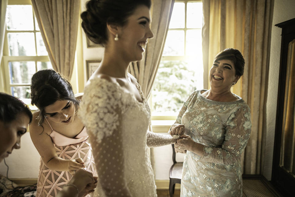 A bride gets helped into her wedding dress by bridesmaids and her mother