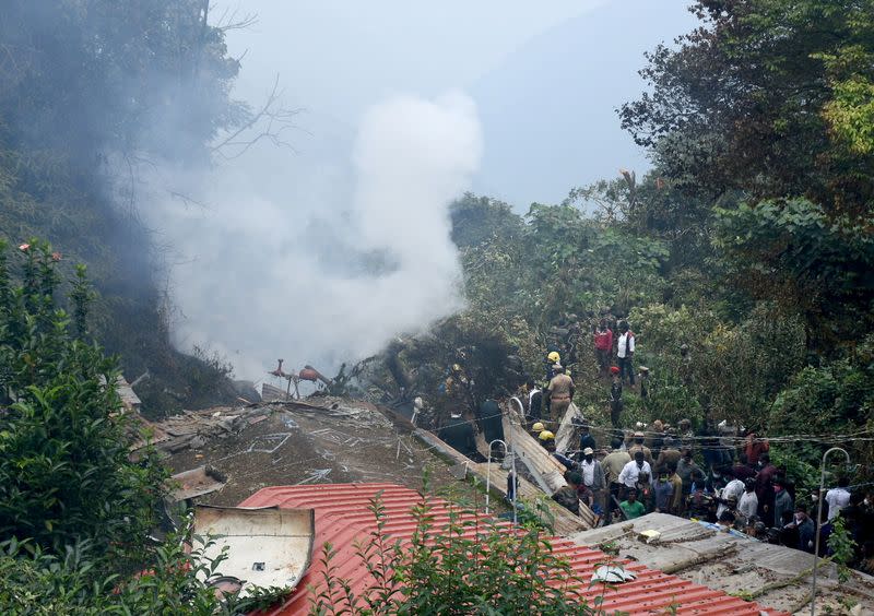 People stand near the debris of the Russian-made Mi-17V5 helicopter after it crashed near the town of Coonoor