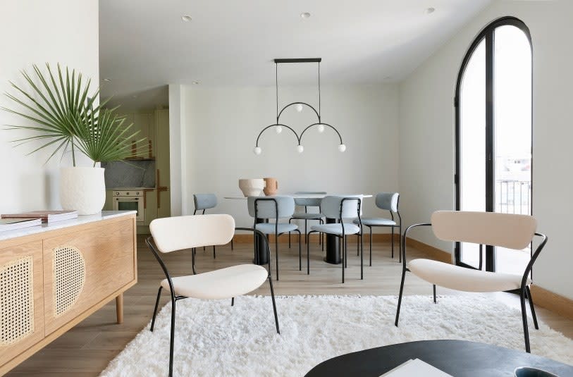 In the dining room, the Coco chairs by Gubi surround the Volà table designed by Noé Prades Studio with a Pholc light fixture hanging above it.