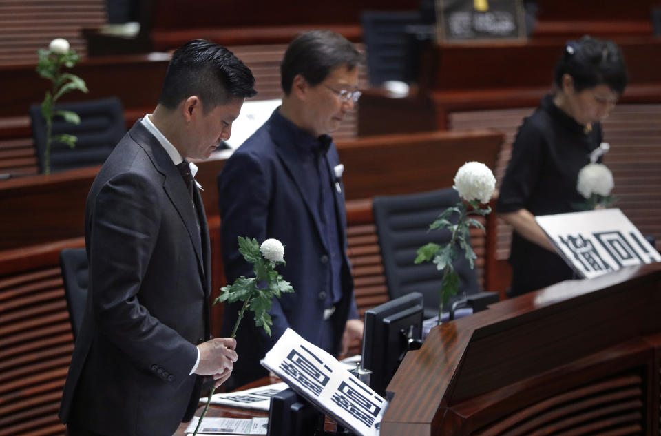 Pro-democracy lawmakers pay a silent tribute to the man who fell to his death on Saturday evening after hanging a protest banner on scaffolding on a shopping mall, at the Legislative Council in Hong Kong, Wednesday, June 19, 2019. Hong Kong lawmakers are meeting for the first time in a week, after massive protests over an extradition bill that eventually was suspended.(AP Photo/Vincent Yu)