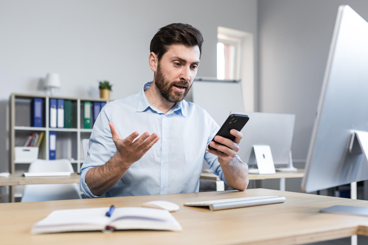 surprised and shocked businessman in the office, man looks at the phone screen, reads the news online