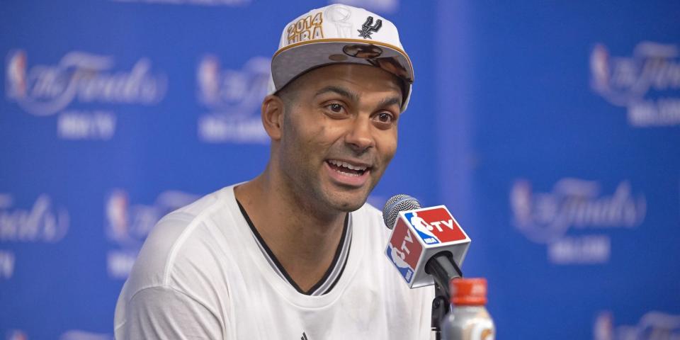 Tony Parker smiles while sitting at a press conference after the Spurs won the 2014 NBA Finals.