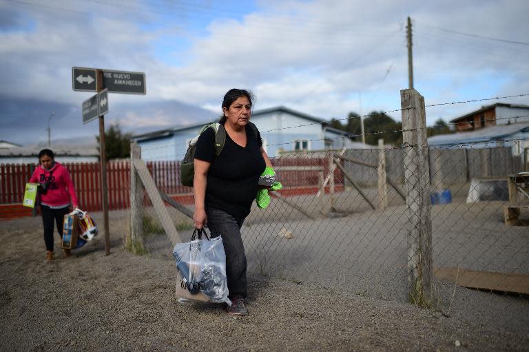 Local residents walk along a street covered with ashes from the Calbuco volcano at La Ensenada, southern Chile, on April 25, 2015