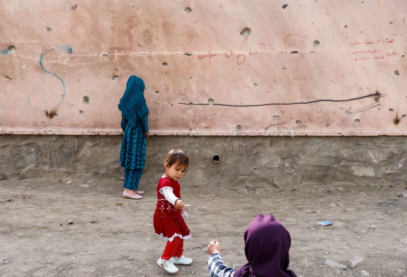 FILE PHOTO: Children stand next to a damaged wall at the site of a car bomb blast that targeted schoolgirls in Kabul