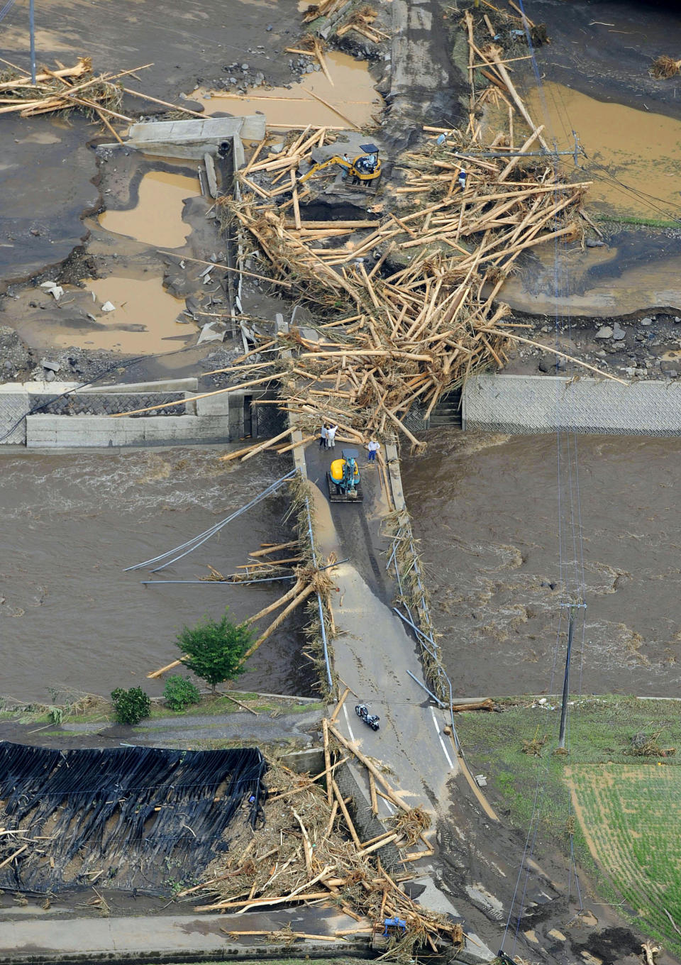 Riverbanks are covered with mud and woods carried by floodwater in Takeda, Kumamoto Prefecture, Japan, Thursday, July 12, 2012. Heavy rains hit southern Japan, triggering flashfloods, mudslides and destroying dozens of homes. (AP Photo/Kyodo News) JAPAN OUT, MANDATORY CREDIT, NO LICENSING IN JAPAN, CHINA, HONG KONG, SOUTH KOREA AND FRANCE