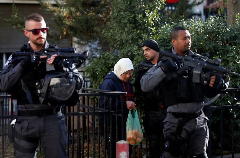 Israeli security forces stand guard as an elderly Palestinian woman walks past in Jerusalem