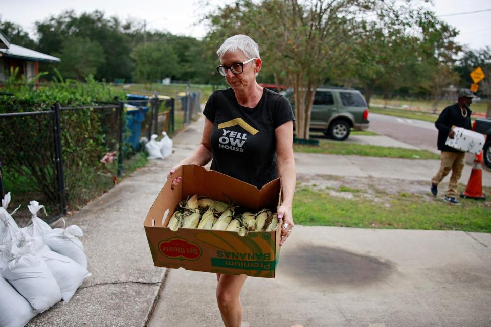 Hope McMath carries fresh produce that was distributed alongside sandbags on Ken Knight Drive North Wednesday as Jacksonville residents prepared for Hurricane Ian to impact the area,