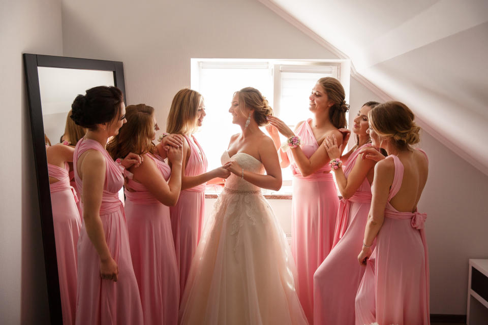 A woman in a wedding dress with her bridesmaids wearing pink