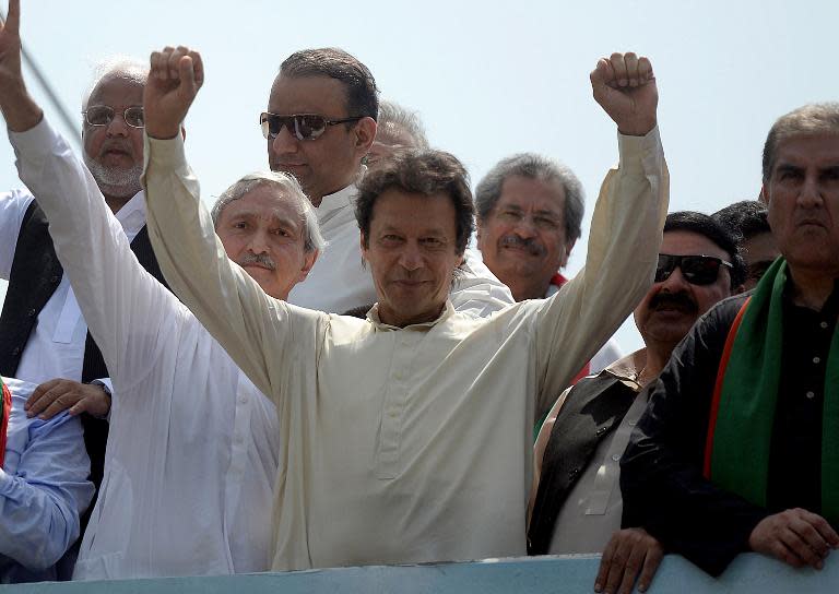 Pakistan cricketer-turned-politician Imran Khan (C) raises his arms as he leads a protest march from Lahore to Islamabad against the government, in Lahore on August 14, 2014