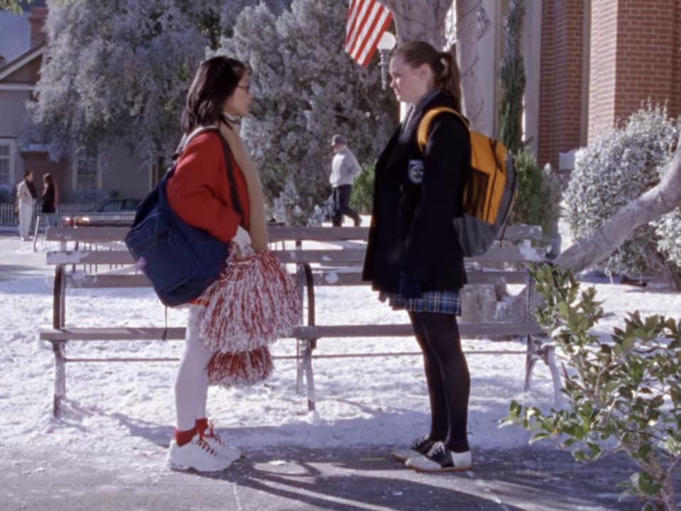 lane in a cheerleading uniform and rory in her chilton uniform in stars hollow on gilmore girls