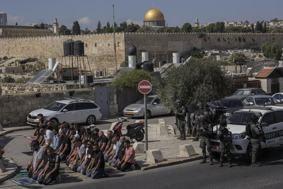 Palestinian worshippers pray outside Jerusalem's Old City while Israeli forces stand guard, Friday, Oct. 13, 2023. At Al-Aqsa Mosque in Jerusalem, Israeli police had been permitting only older men, women and children to the sprawling hilltop compound for prayers, trying to prevent the potential for demonstration as tens of thousands attend on a typical Friday. (AP Photo/Mahmoud Illean)