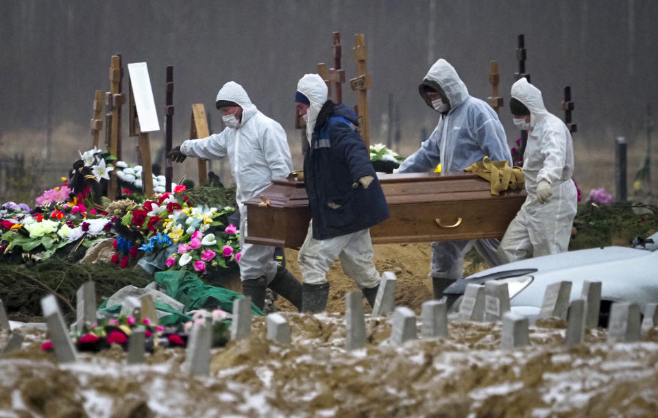 FILE In this file photo taken on Tuesday, Dec. 15, 2020, Grave diggers wearing protective suits carry the coffin of a COVID-19 victim in the section of a cemetery reserved for coronavirus victims in Kolpino, outside St.Petersburg, Russia. Russia's updated statistics on coronavirus-linked deaths showed that over 100,000 people with COVID-19 had died in the pandemic by December, a number much higher than previously reported by government officials. According to the data released Monday by Russia's state statistics agency, Rosstat, a total of 116,030 people with COVID-19 died in Russia between April and November. The count included cases where the virus was not the main cause of death and where the virus was suspected but not confirmed. (AP Photo/Dmitri Lovetsky, File)