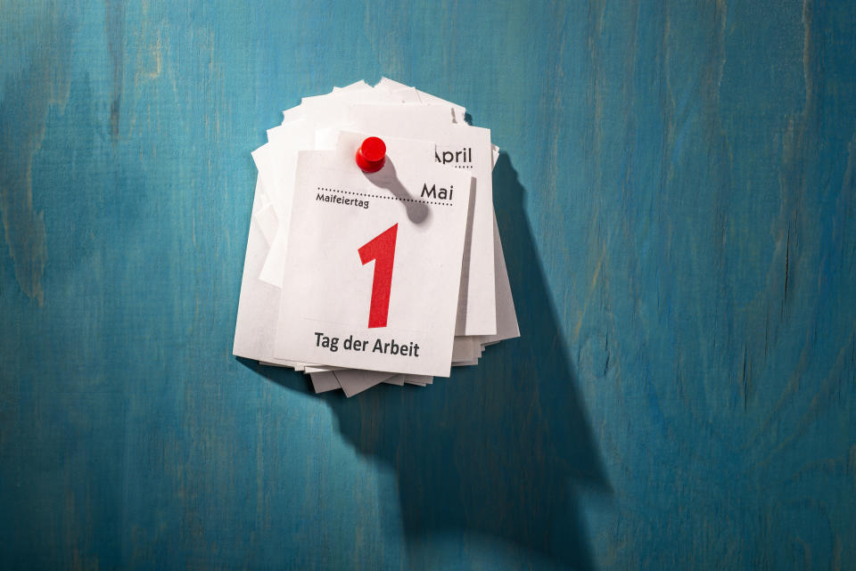 Calendar sheets are pinned to a wall. The top sheet shows May 1 with the inscription "Labour Day".