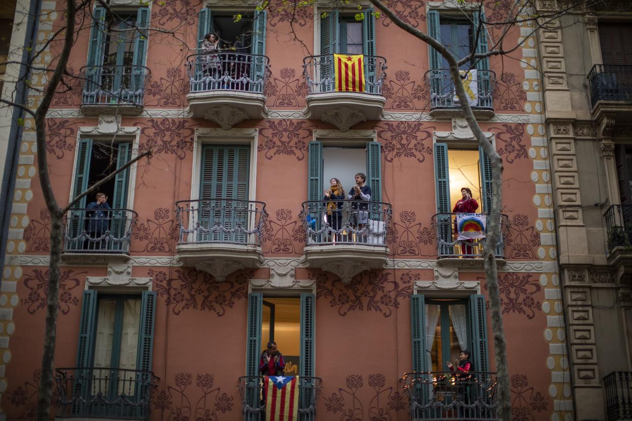 People applaud from their houses in support of the medical staff that are working on the COVID-19 virus outbreak in Barcelona, Spain, on Sunday, March 29, 2020.