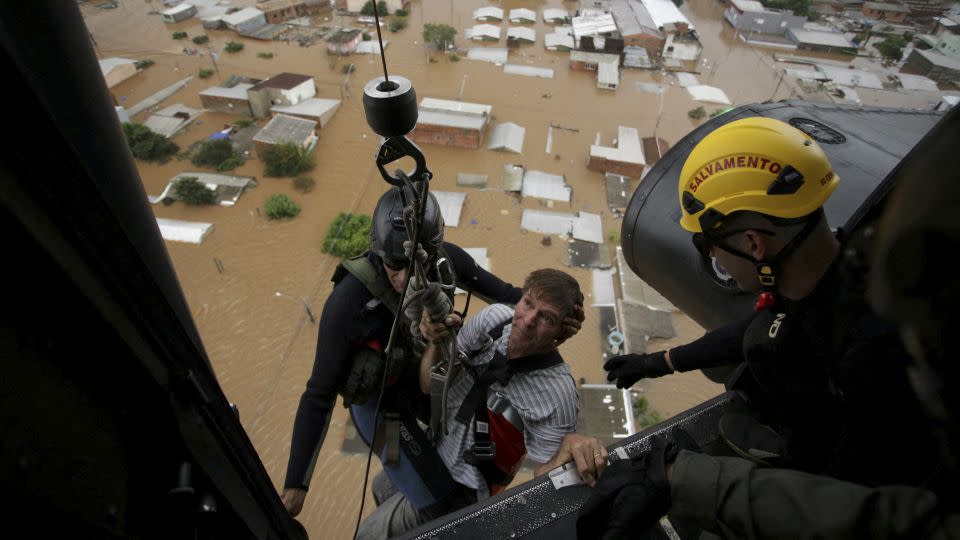 Military firefighters rescue a man using a helicopter. - Renan Mattos/Reuters