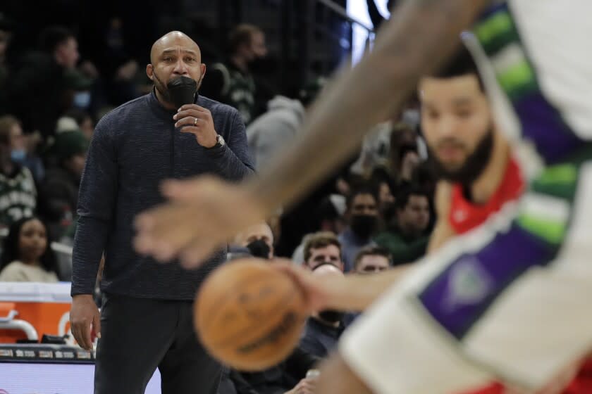 Milwaukee Bucks assistant coach Darvin Ham pulls on his mask as he coaches from the sideline