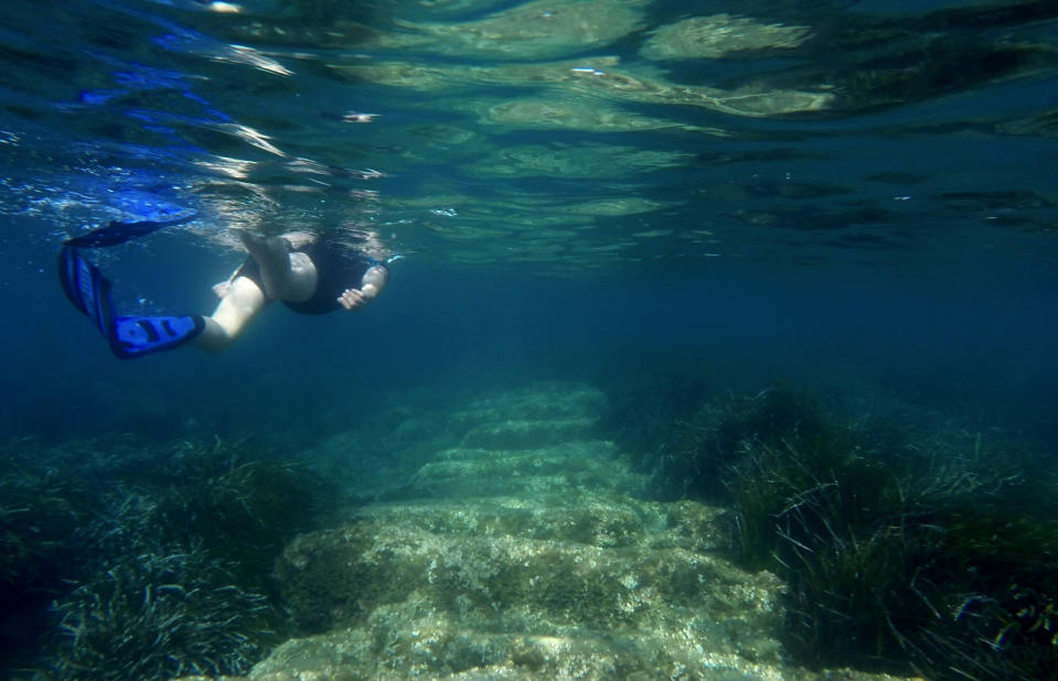 Cyprus Antiquities Department official Yiannis Violaris snorkels over submerged stone remains of the ancient harbor next of Amathus ancient city, in the eastern Mediterranean island of Cyprus, on Thursday, July 1, 2021. Lying just a few feet underwater a mere 200 feet off the coastline near the resort town of Limassol, this 2,400 year-old harbor said to be built Alexander the Great's successors will soon be Cyprus' newest tourist attraction where adventurous holidaymakers could snorkel over its submerged stone remains. (AP Photo/Petros Karadjias)